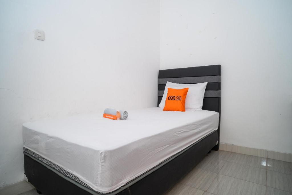 a bed with an orange pillow on top of it at KoolKost Syariah near Stasiun Rawa Buntu (Minimum Stay 6 Nights) in Tangerang