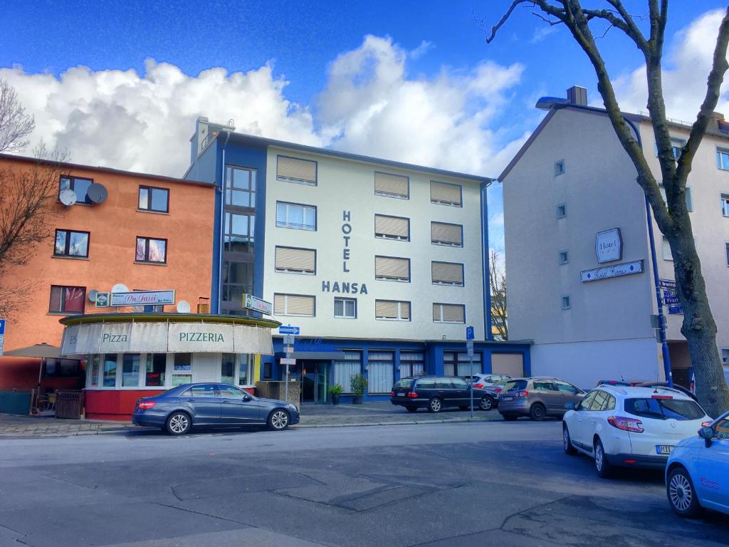 un gran edificio con coches estacionados en un estacionamiento en Hotel Hansa, en Offenbach