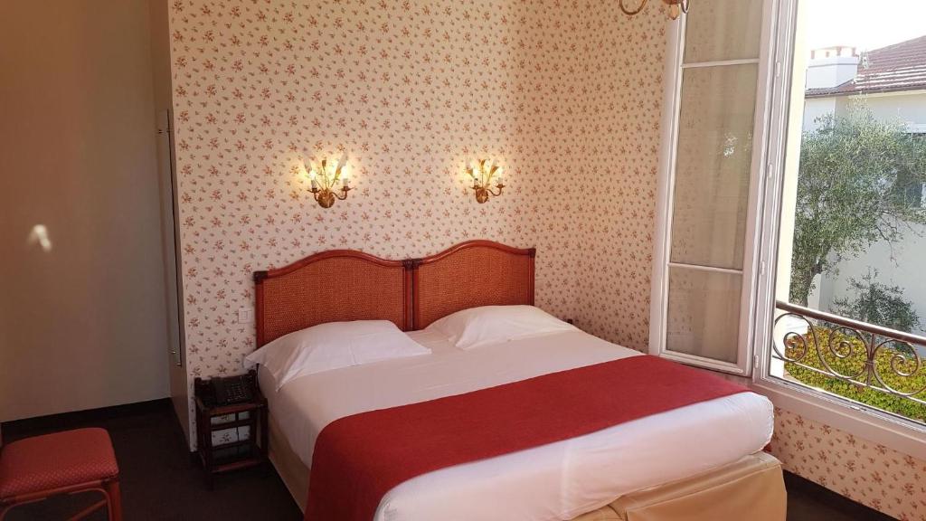 a bedroom with a bed with a red blanket and a window at Hôtel de Charme Brise Marine in Saint-Jean-Cap-Ferrat