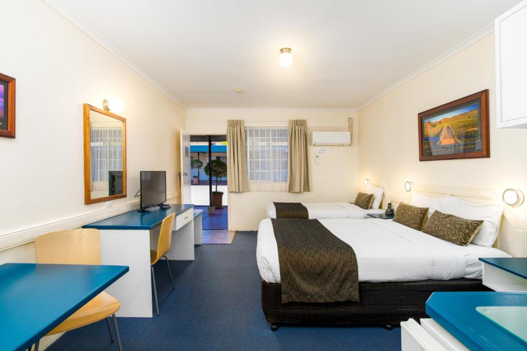 a hotel room with two beds and a desk at Applegum Inn in Toowoomba