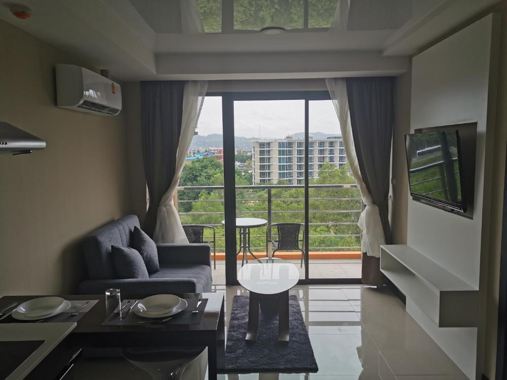 a living room with a couch and a large window at APARTMENTS MBC in Mai Khao Beach