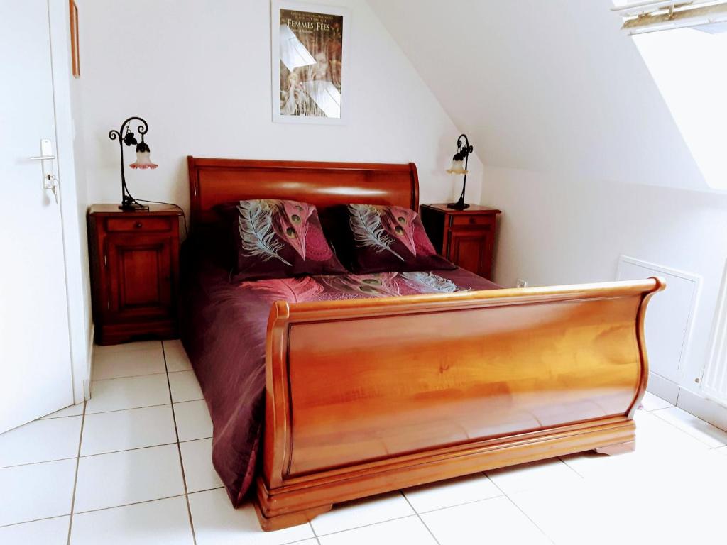 een slaapkamer met een houten bed en 2 nachtkastjes bij L'atelier des Fées de l'Aff in Paimpont