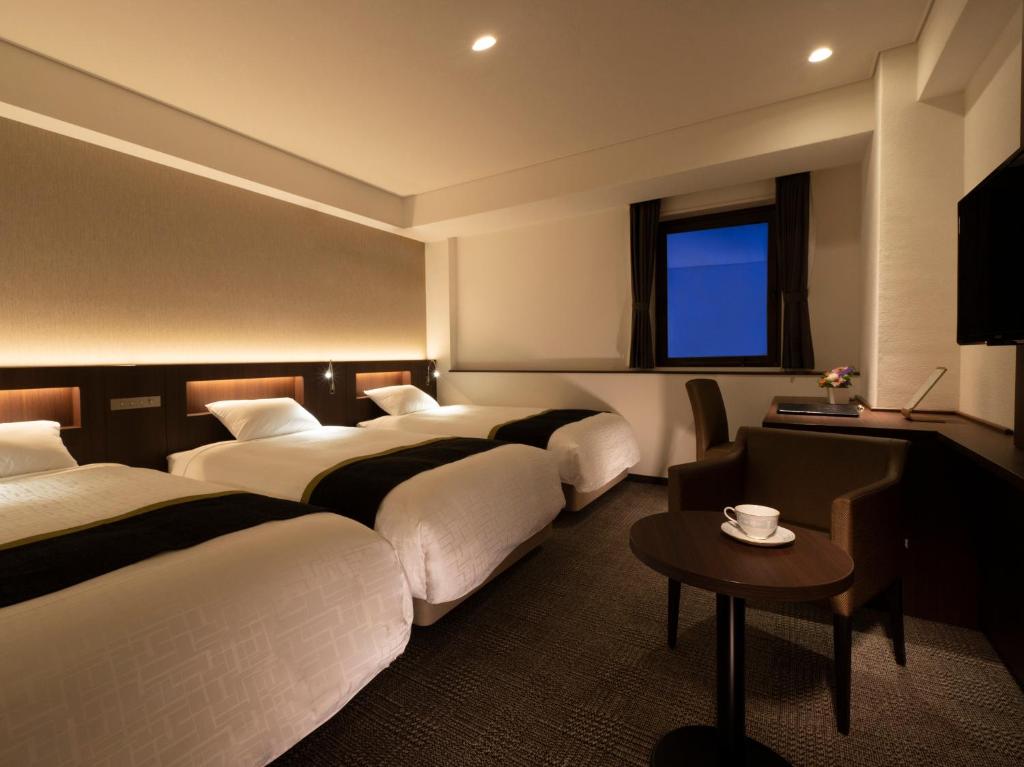 名古屋市にあるプリンセスガーデンホテルのベッド4台とテーブルが備わるホテルルームです。