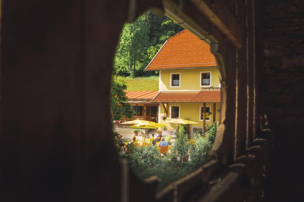 una ventana con vistas a una casa con jardín en Berggasthof Karlbauer en Lendorf