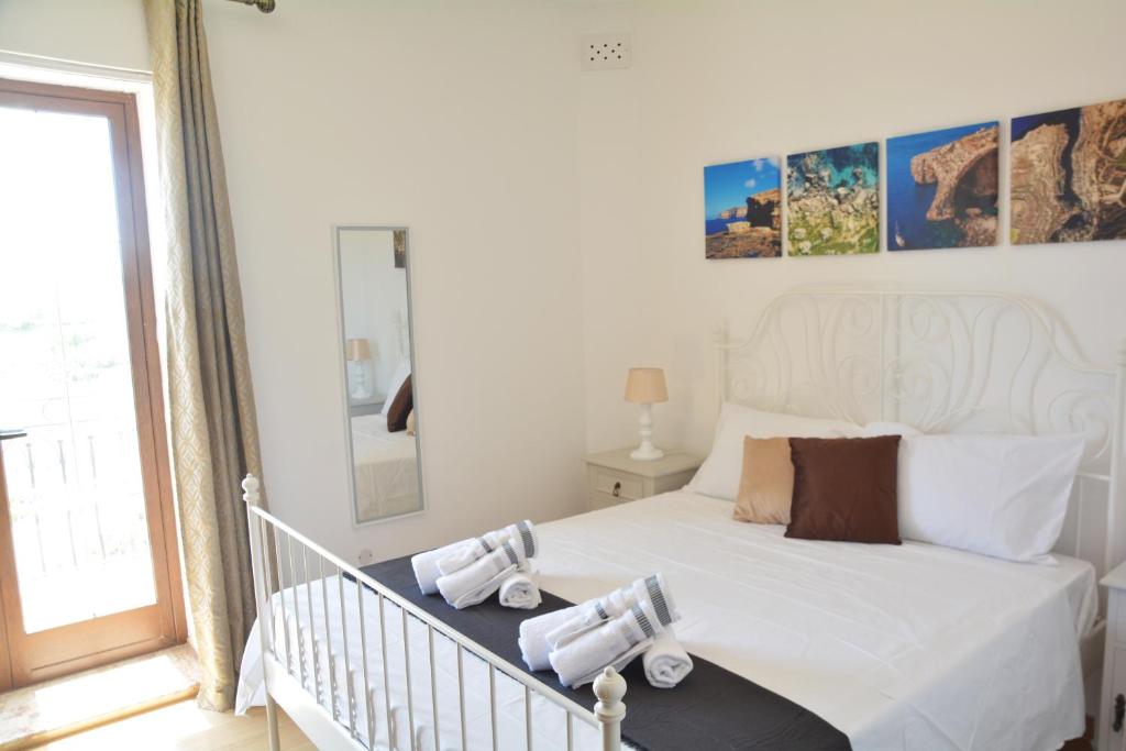 Un dormitorio con una cama blanca con toallas. en Joseluce en Gudja