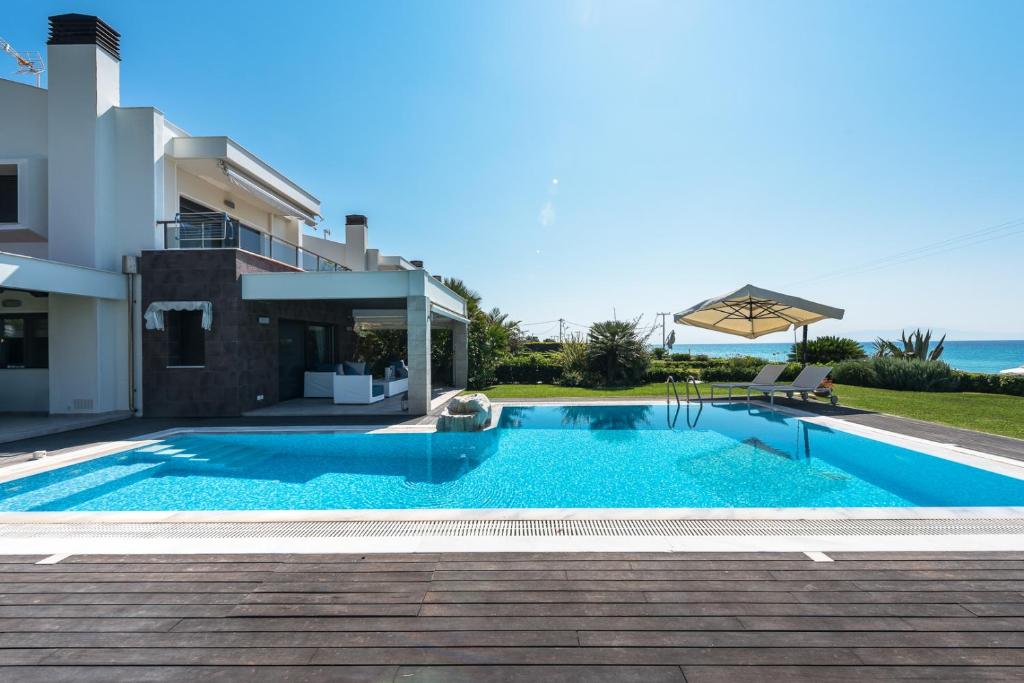 a villa with a swimming pool in front of a house at Possidi Villa Glamour by Luxlikehome in Possidi