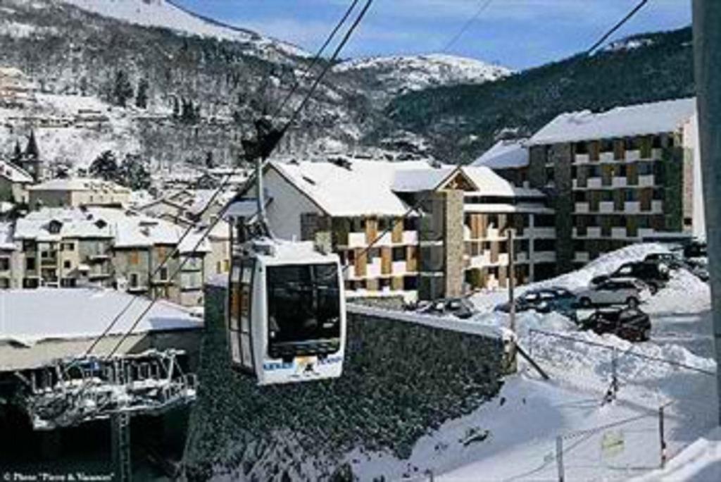 Hébergement Coup de Coeur في آكس ليه تيرم: يوجد ترام على مصعد التزلج في مدينة بها ثلج