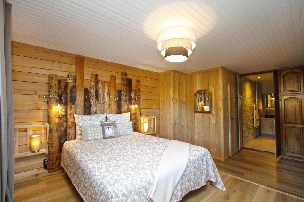 - une chambre avec un lit dans une pièce dotée de murs en bois dans l'établissement Au Domaine de PY, à Le Valtin