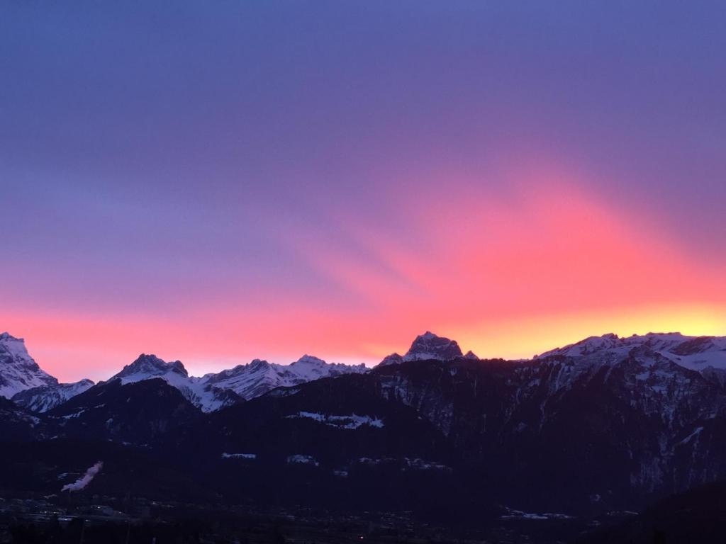 una puesta de sol sobre las montañas con un cielo rojo en Les Dents-du-Midi en Monthey