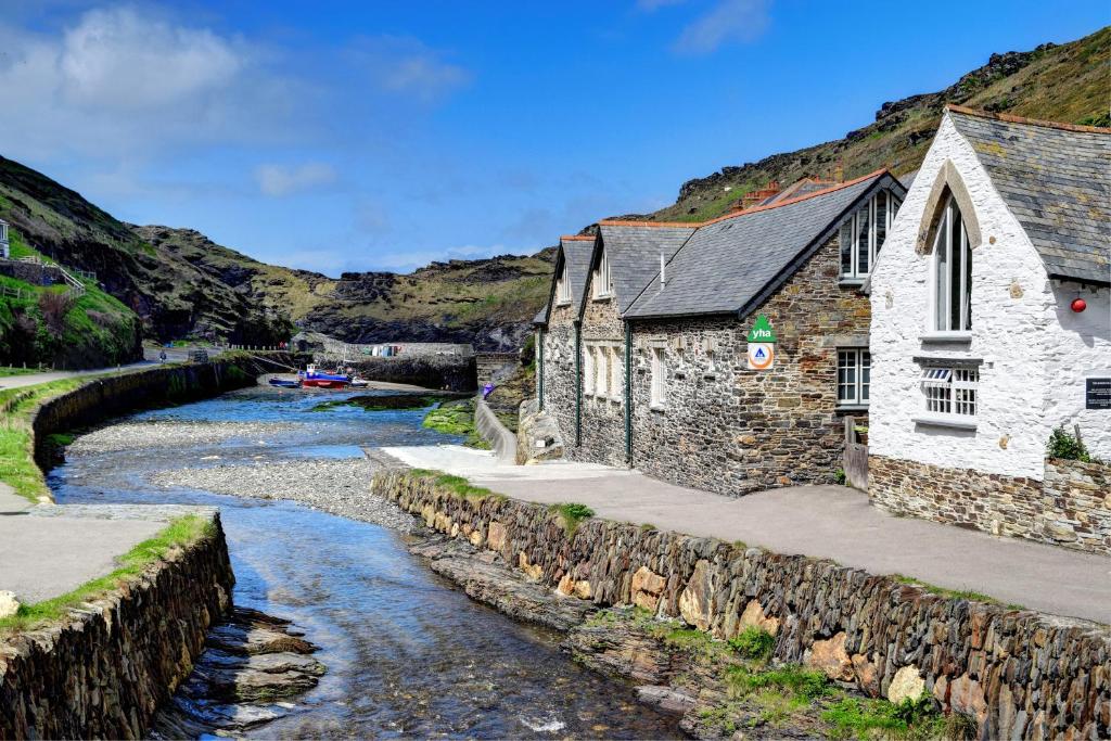 a church next to a river with a stone wall at YHA Boscastle in Boscastle