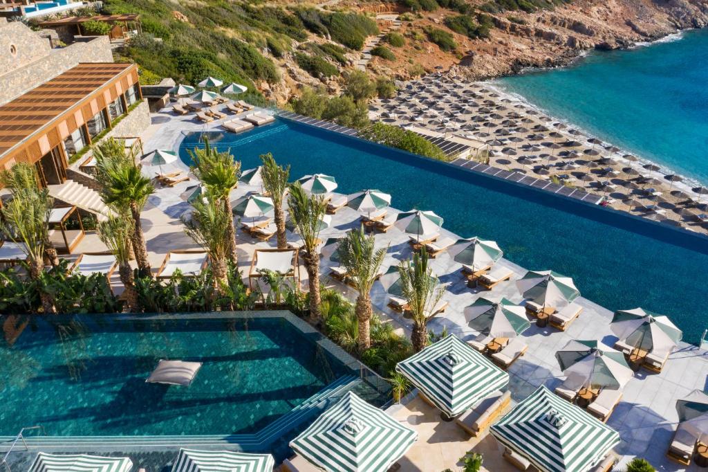 an aerial view of a resort swimming pool with umbrellas at Daios Cove in Agios Nikolaos