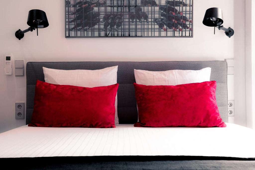 een bed met twee rode kussens en een zwart hoofdeinde bij Boutique Hotel ZIES in Utrecht