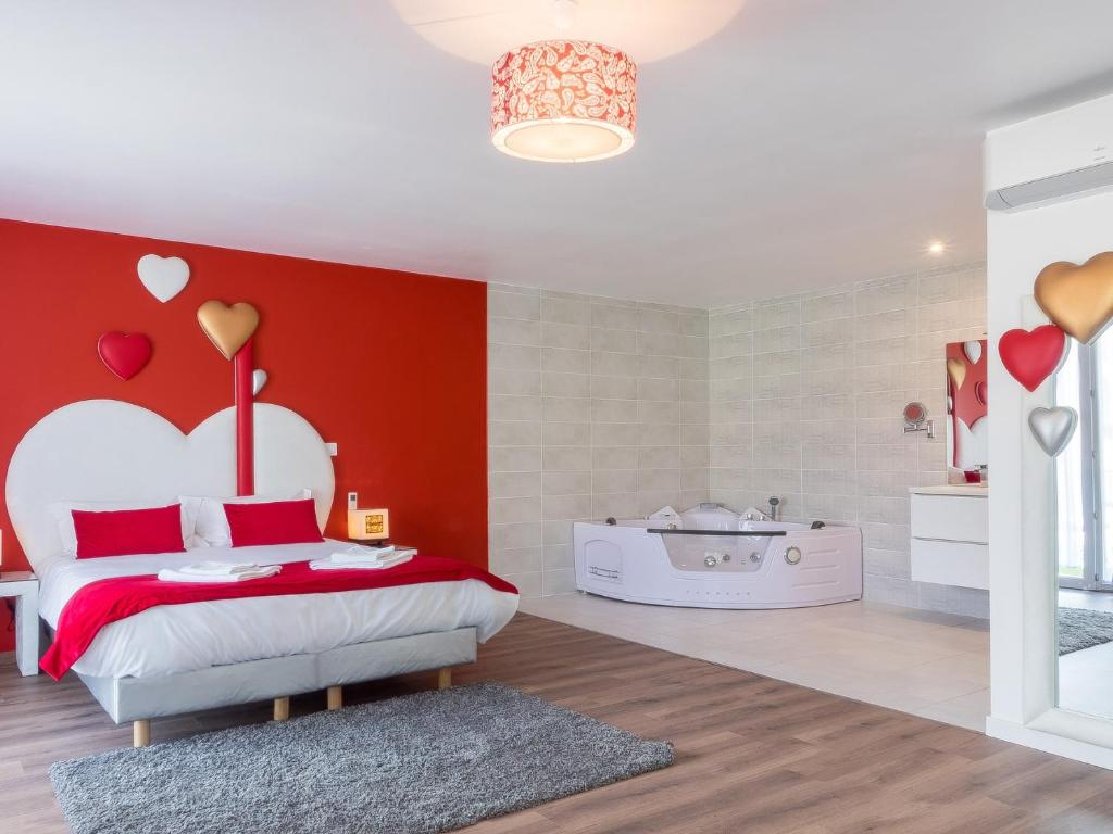 una camera da letto con una parete rossa, un letto e una vasca di Hôtel Domaine des Pierres Dorées a Ternand
