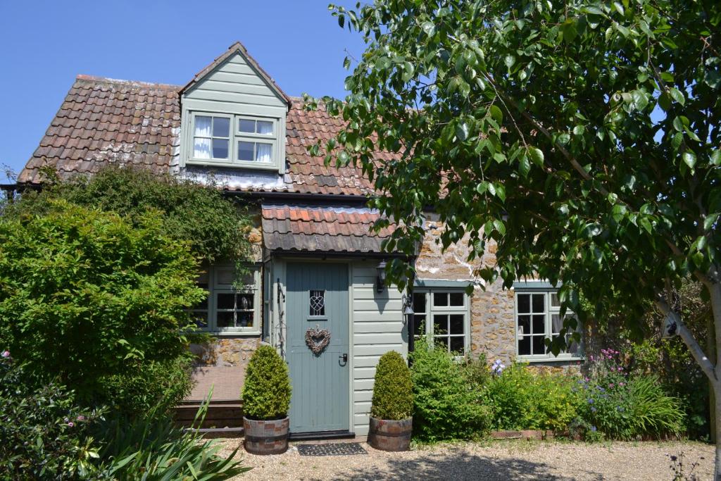 a cottage with a blue door in the garden at Chiddy Nook Cottage in Chideock