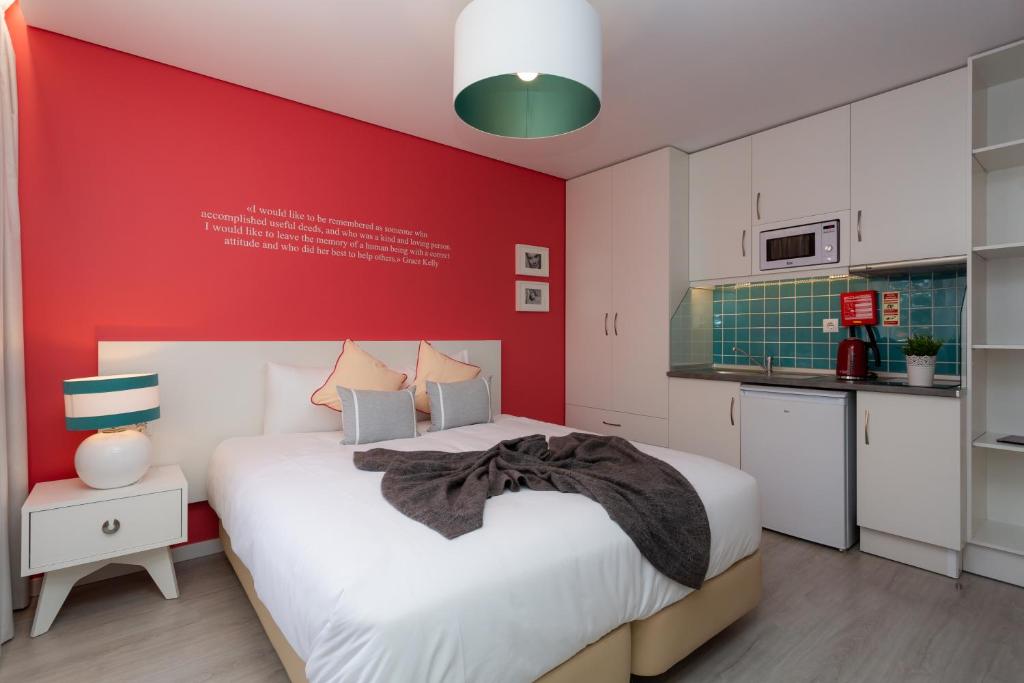 a bedroom with a white bed and red wall at Chic Studios in Parede