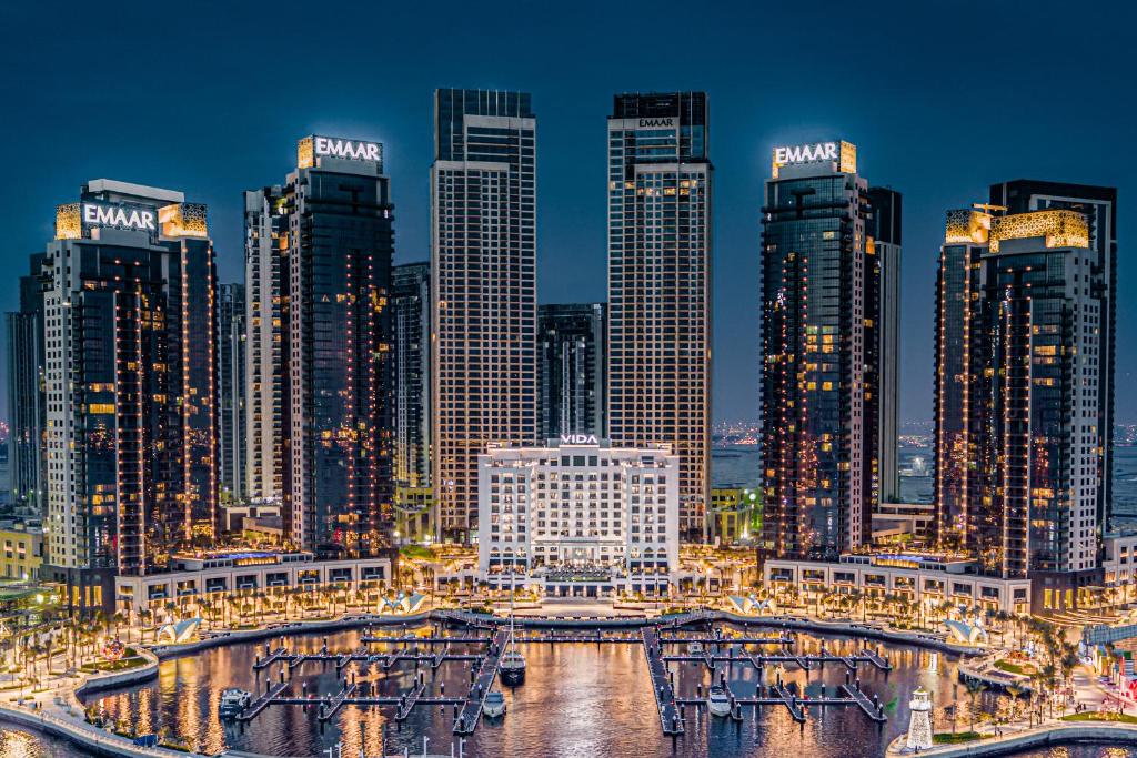 een groep van hoge gebouwen in een stad 's nachts bij Vida Creek Harbour in Dubai