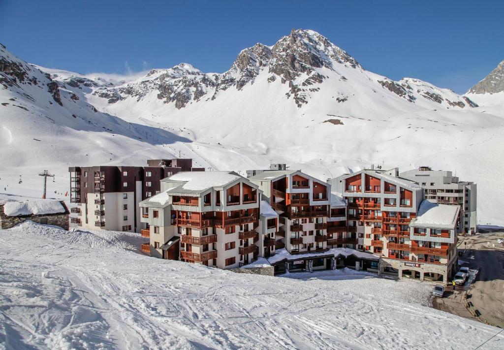 un bâtiment dans la neige avec une montagne en arrière-plan dans l'établissement travelski home classic - Résidence Le Hameau du Borsat 3 stars, à Tignes