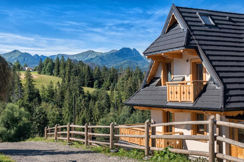 una casa con techo negro y valla de madera en Domek 990m npm en Zakopane
