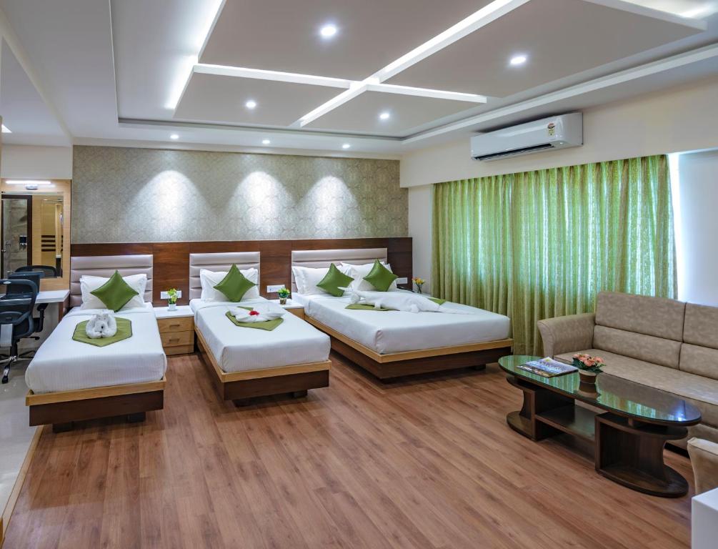 a hotel room with two beds and a couch at Vanusa Residency in Bangalore