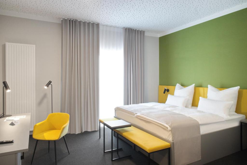 um quarto de hotel com uma cama e uma cadeira amarela em Hotel Adler Münster em Münster