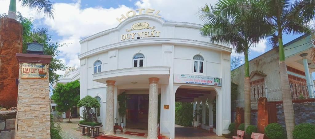 Biały budynek z zegarem na górze w obiekcie HOTEL DUY NHẤT w mieście Phú Nhơn