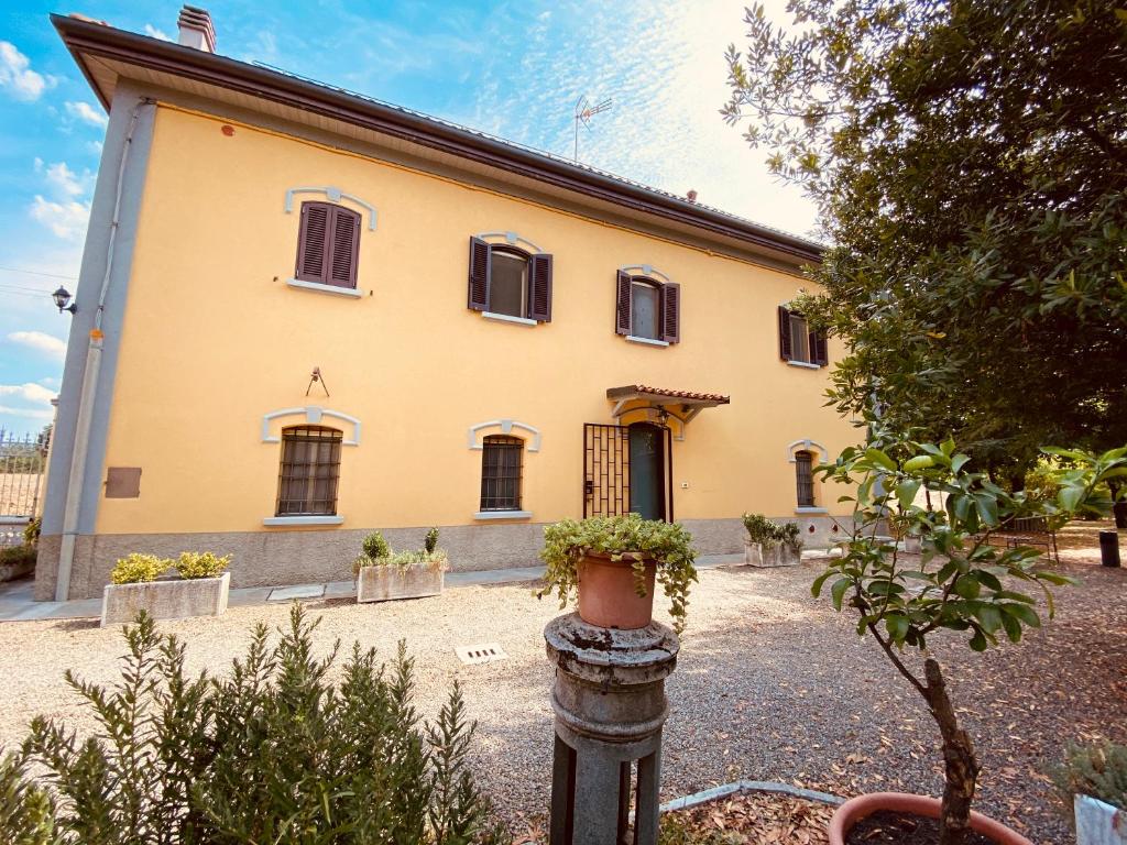un gran edificio amarillo con algunas plantas delante de él en B&B Villino Margherita, en San Lazzaro di Savena