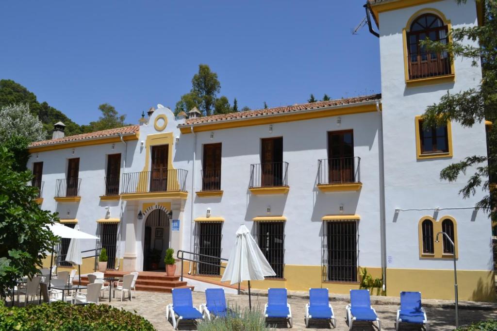 a large white building with blue chairs in front of it at Hotel Humaina in Málaga