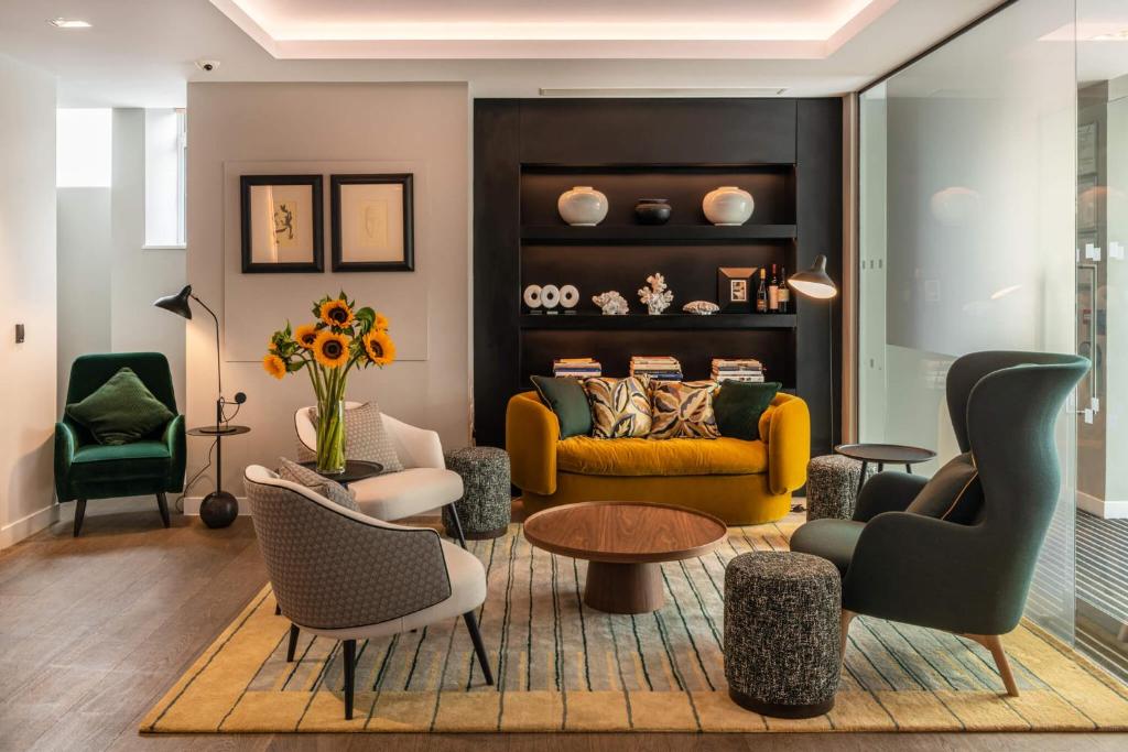 a living room with a yellow couch and chairs at The Resident Victoria in London