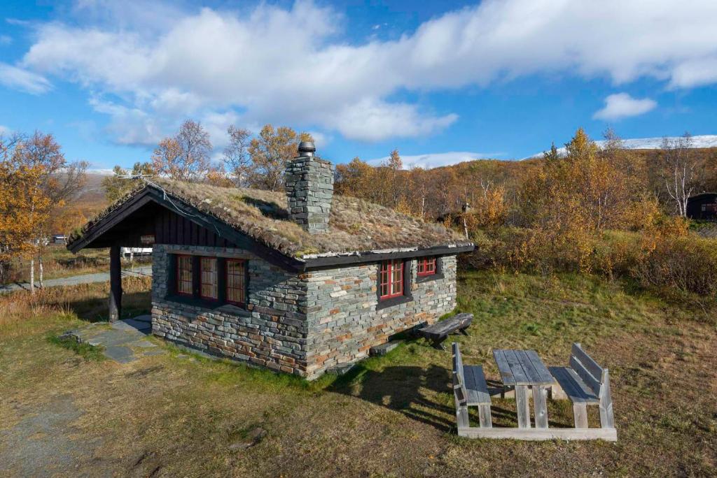 une ancienne maison en pierre avec deux chaises devant elle dans l'établissement Besseggen Fjellpark AS, à Maurvangen