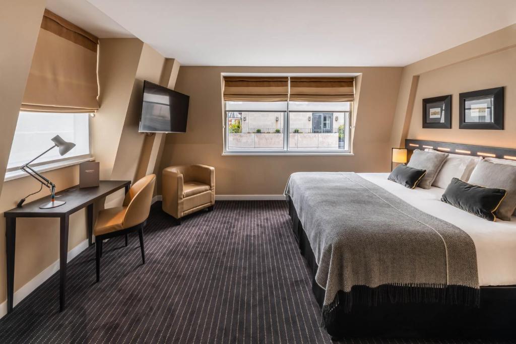 a hotel room with a bed and a desk and a window at The Resident Victoria in London