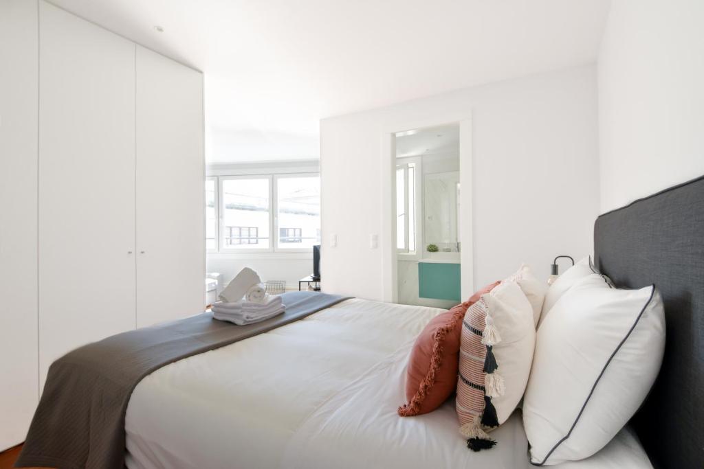 a white bedroom with a large bed with pillows at Free Parking - Aliados 107 Liberty Square in Porto