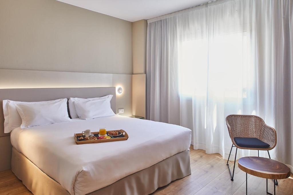 a hotel room with a bed with a tray of food on it at Silken Reino de Aragón in Zaragoza
