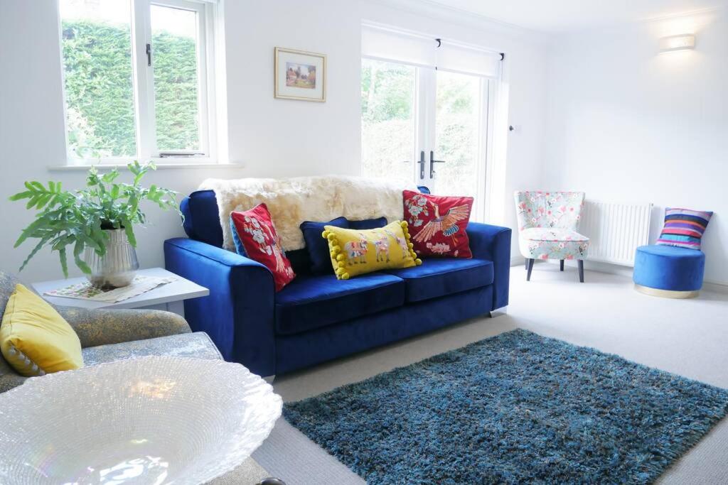 un sofá azul con almohadas coloridas en la sala de estar. en The Croft a lovely town house in the centre of Holt with free PARKING for two cars, en Holt