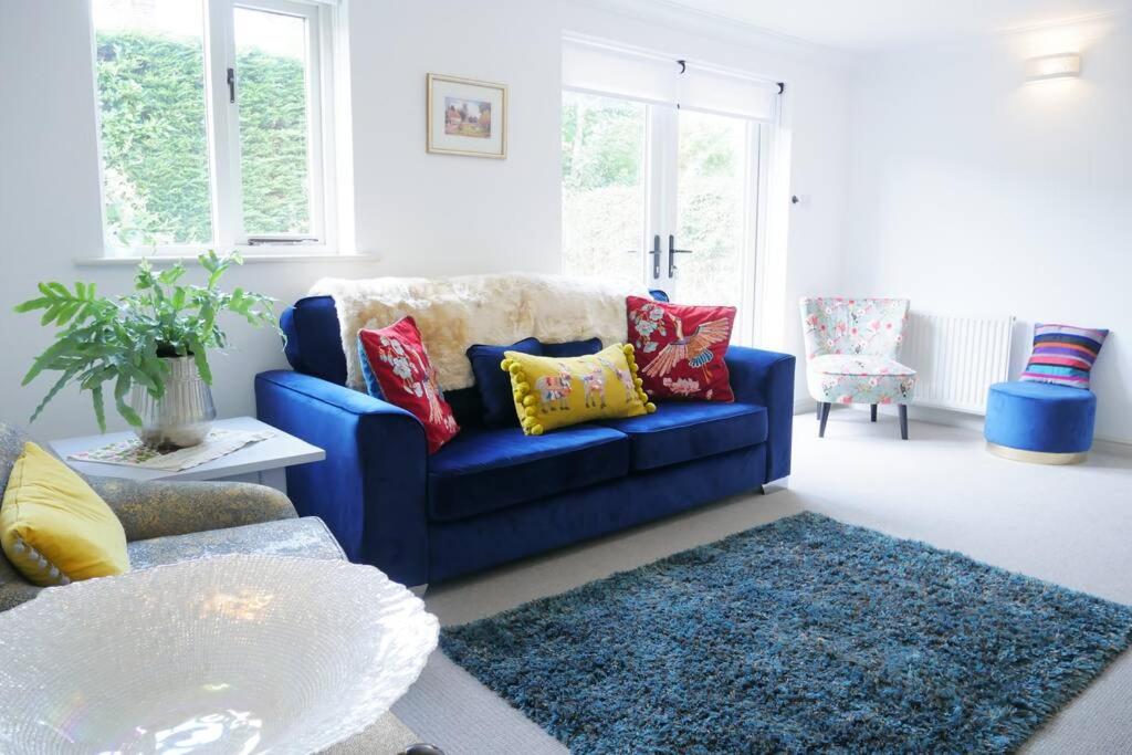 a blue couch with colorful pillows in a living room at The Croft a lovely town house in the centre of Holt with free PARKING for two cars in Holt