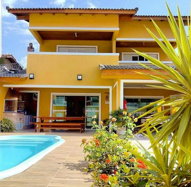 uma casa amarela com uma piscina em frente em Pousada Marcos no Guarujá