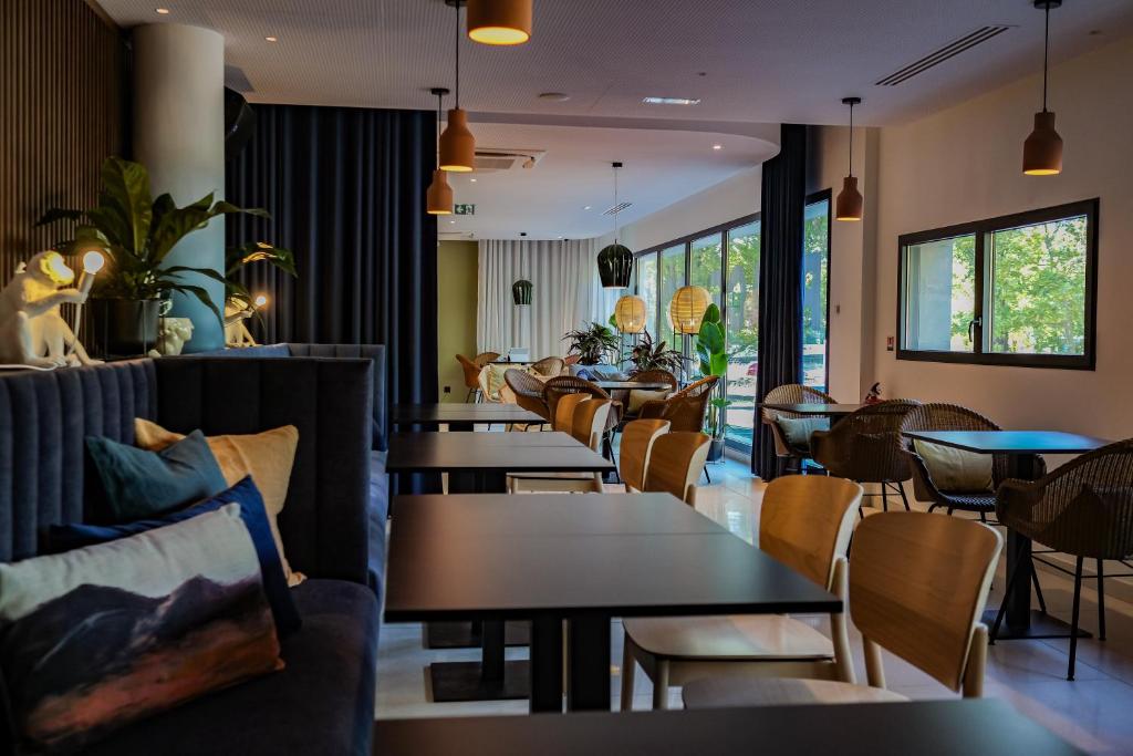 a restaurant with tables and chairs and windows at Live Hotels Bordeaux Lac in Bordeaux