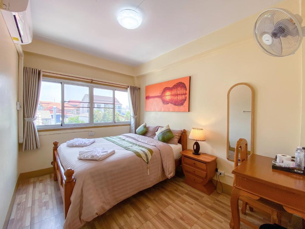 Kavil Guesthouse في شيانغ ماي: غرفة نوم بسرير ومكتب ونافذة