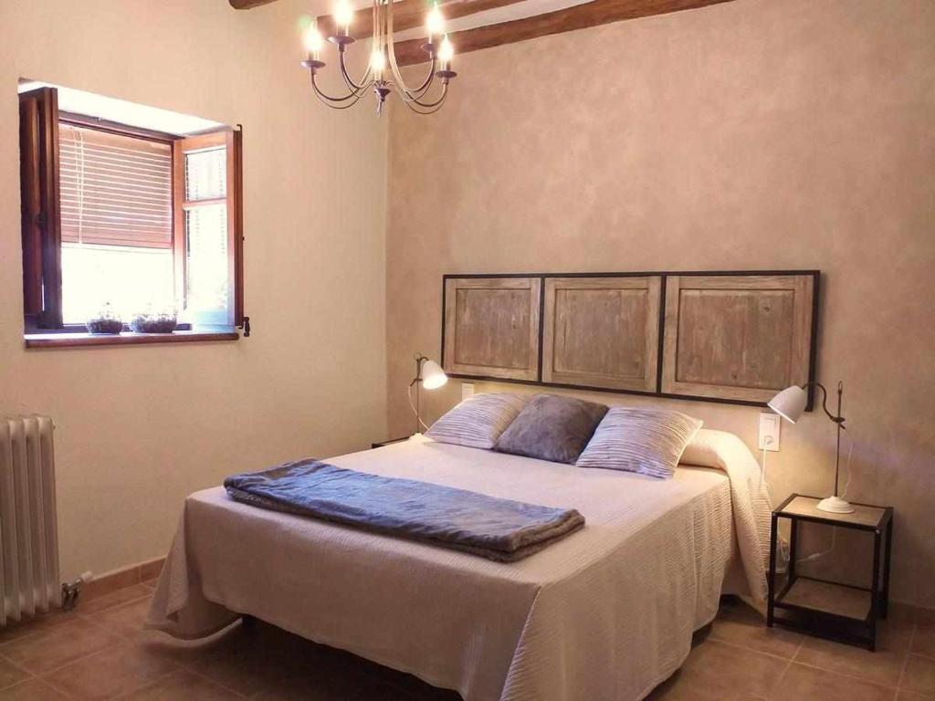 a bedroom with a bed and a window and a chandelier at Casa Rural els Esclopets in Sanahuja