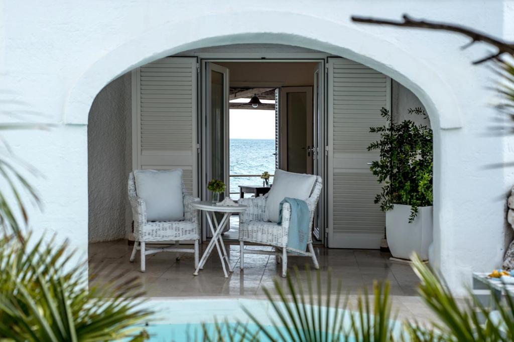 a patio with chairs and a table and the ocean at La Peschiera in Monopoli