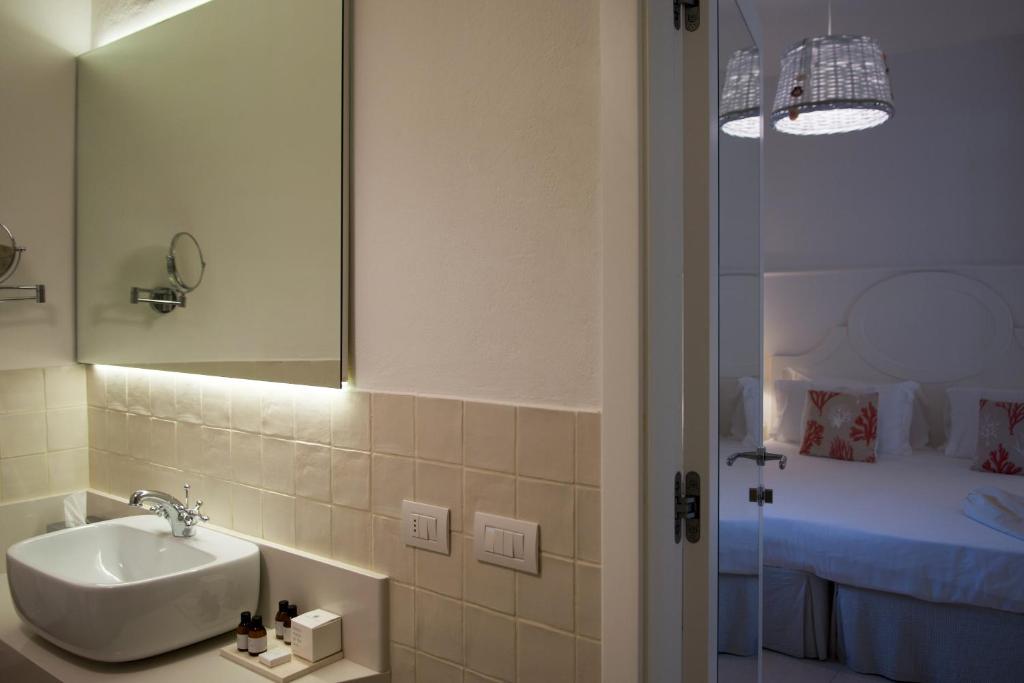a bathroom with a sink and a mirror and a bed at La Peschiera in Monopoli