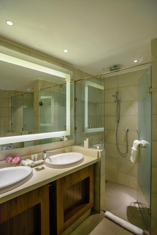 a bathroom with two sinks and a shower and a mirror at Crowne Plaza Nairobi Airport by IHG in Nairobi