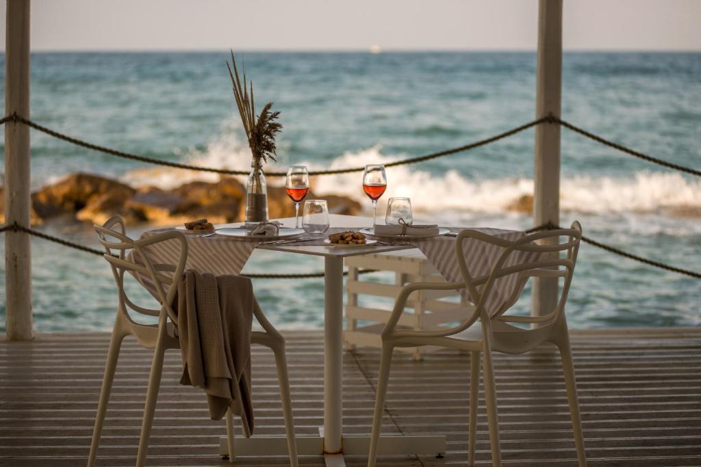 a table with two chairs and wine glasses on the beach at La Peschiera in Monopoli