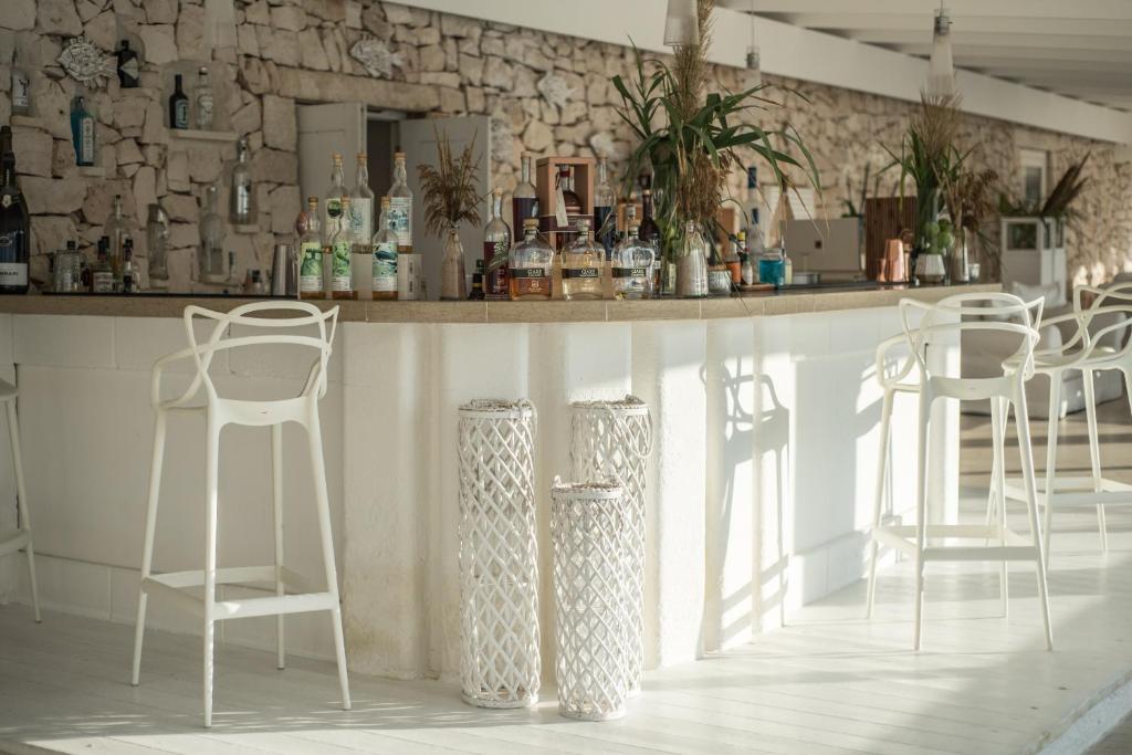 a bar with white stools in a room with a stone wall at La Peschiera in Monopoli