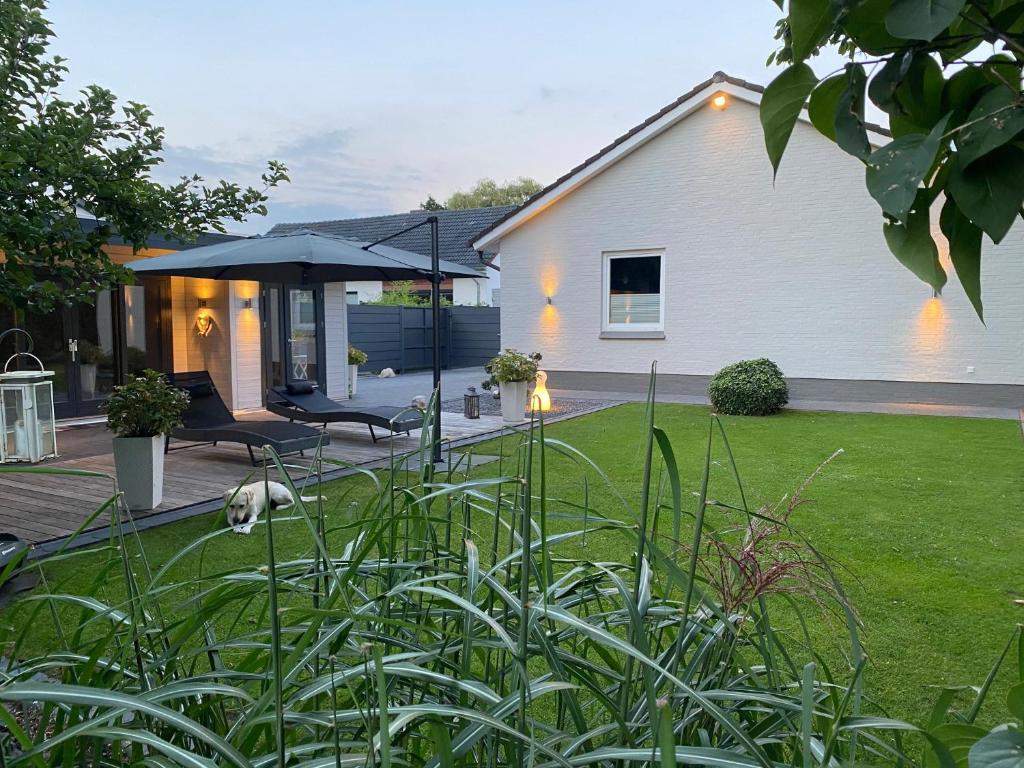 Cette maison dispose d'une terrasse avec un parasol. dans l'établissement Family Ferienhaus Ennens, à Rhauderfehn
