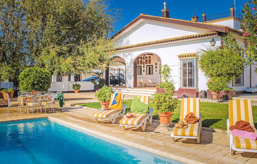 une maison dotée d'une piscine avec des chaises et une table dans l'établissement CASA RURAL LA FLORIDA, MORÓN de la FRONTERA, à Morón de la Frontera