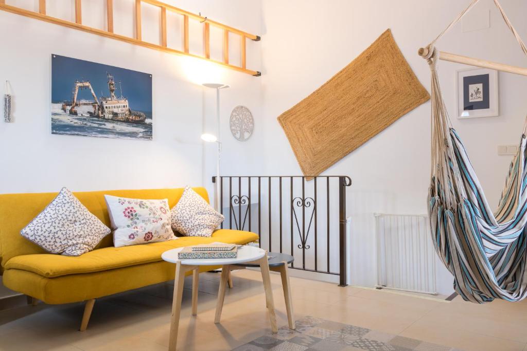 salon z żółtą kanapą i stołem w obiekcie La Vila Feliz, gemütliche private Duplex-Ferienwohnung im typischen Fischerhaus mit fantastischem Meerblick w mieście Villajoyosa