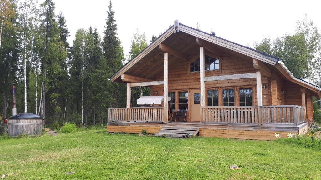 a log cabin with a large deck in a field at Savutaival in Pello