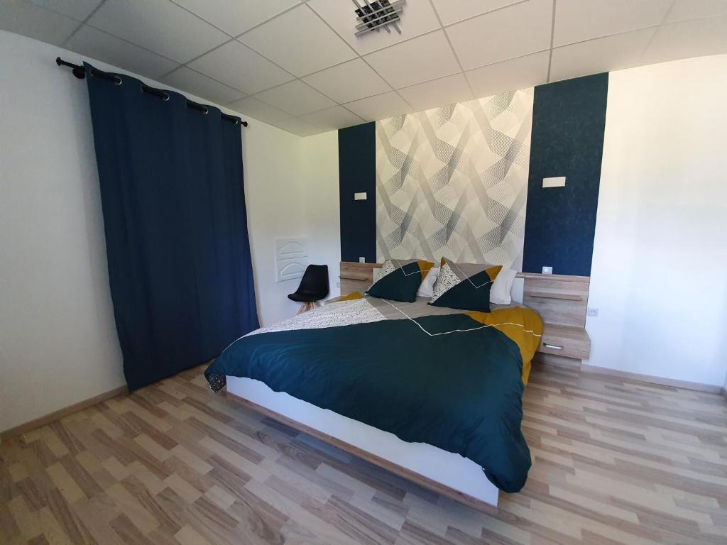 a bedroom with a large bed and blue curtains at Le Pont Sée in Romille