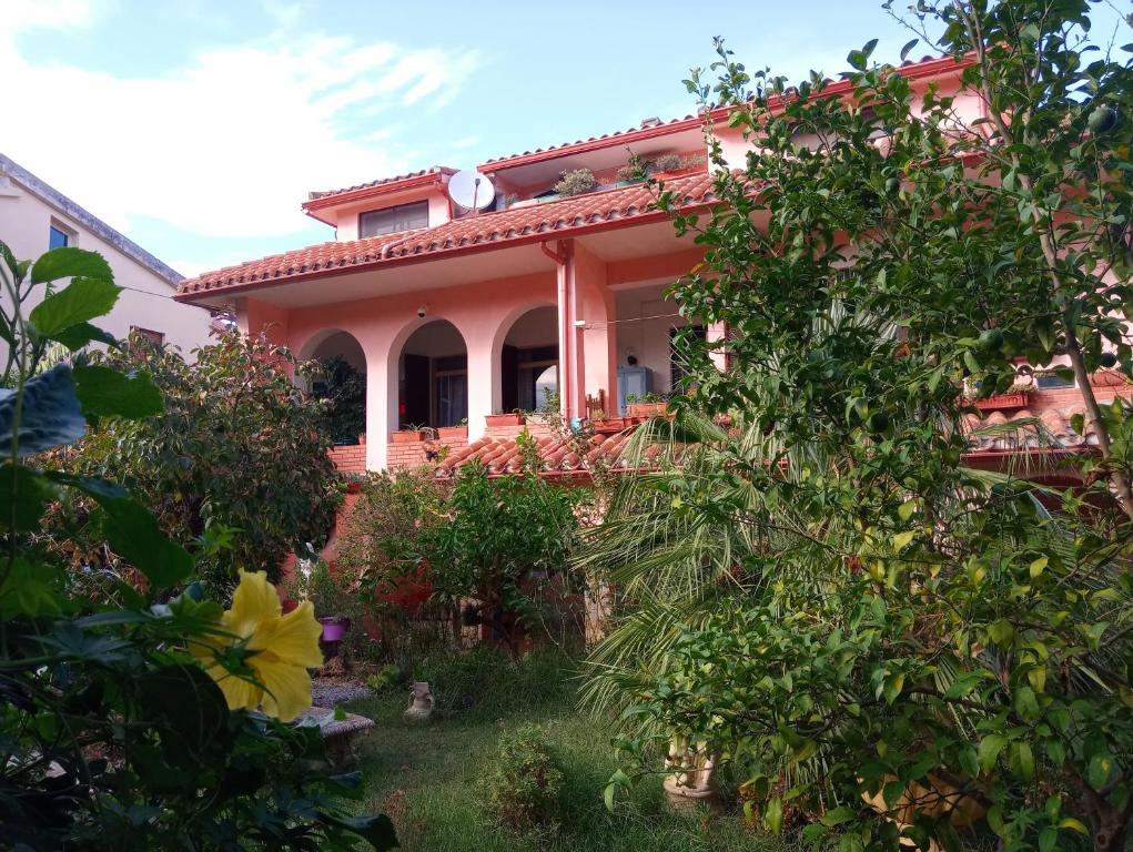 une maison rose avec des arbres devant elle dans l'établissement Villa Corrias, à Siliqua