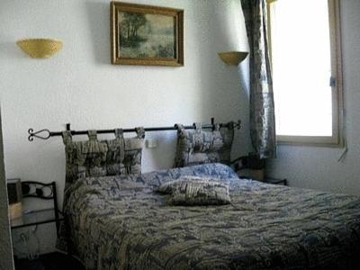 a bedroom with a bed in a room with a window at Logis Hôtel Le Vieil Amandier in Trigance
